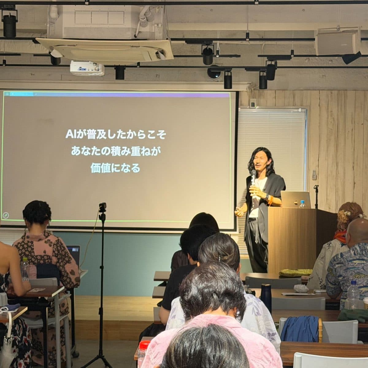 講座で登壇する高橋直寛。スライドには「AIが普及したからこそ あなたの積み重ねが 価値になる」