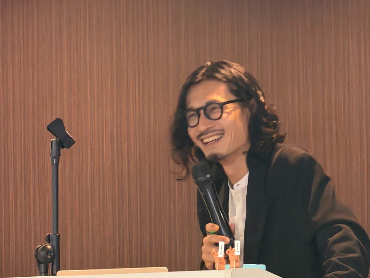 演台でマイクを持ち、笑顔で話す高橋直寛